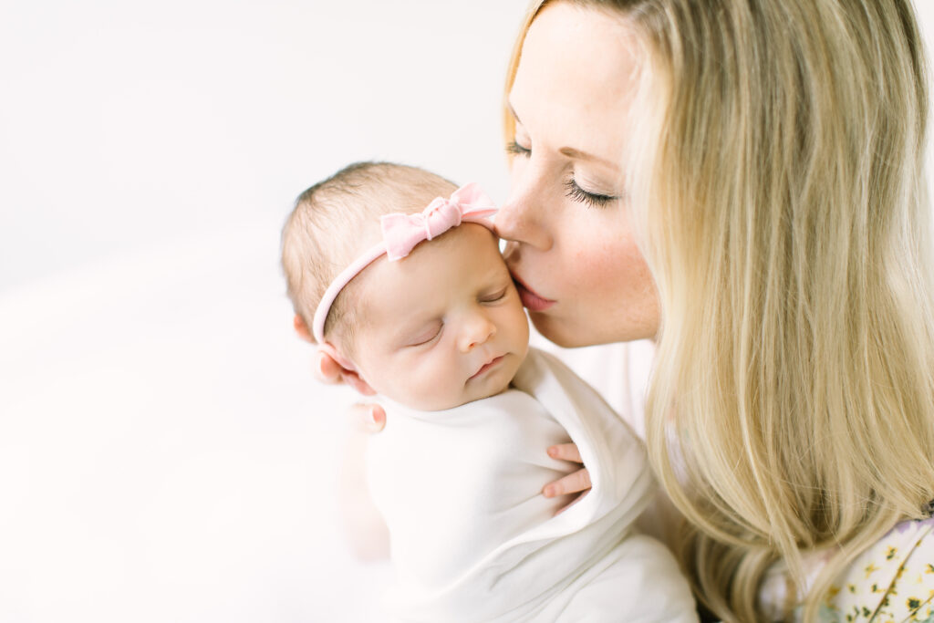 mom kissing baby, baby, newborn, beautiful mom and baby, sleeping baby, swaddled baby, mom and baby, baby with hair bow, newborn photography